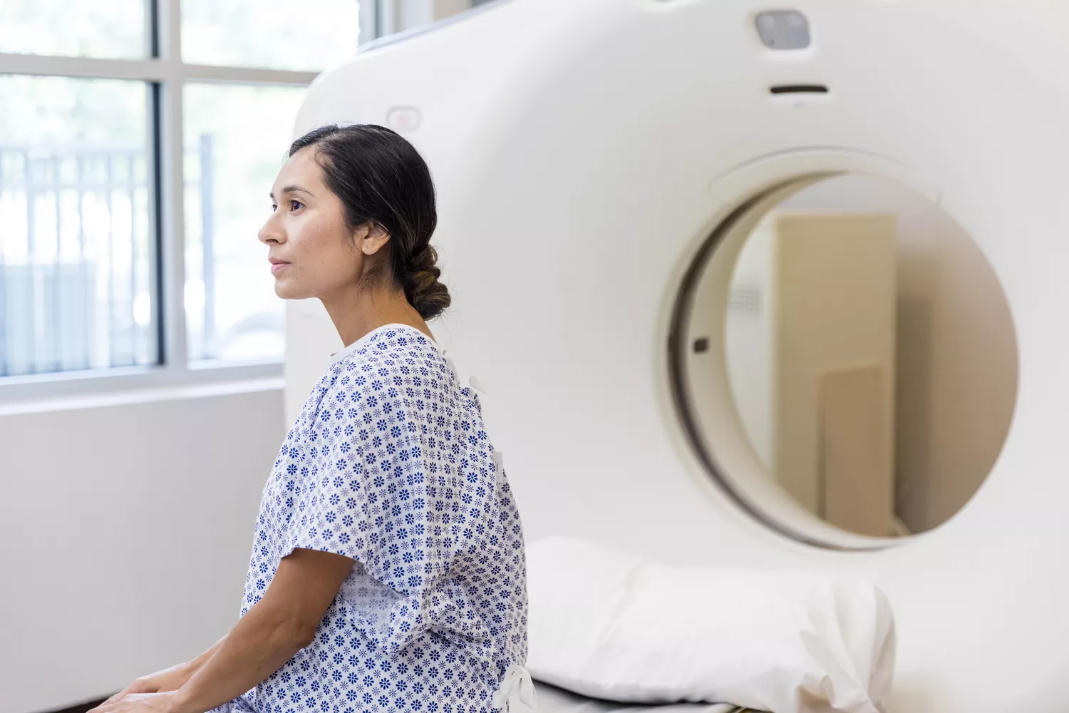 A woman waiting in a medical facility for a diagnostic CT scan.