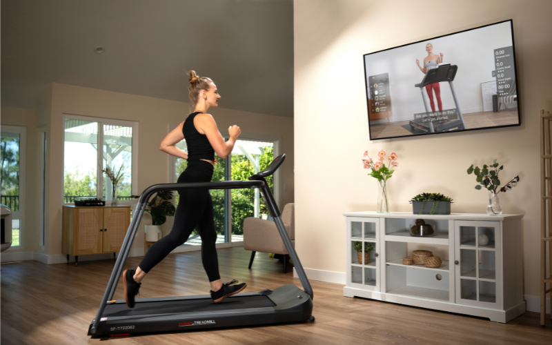 A person using a treadmill with extended full-length safety handrails for balance.