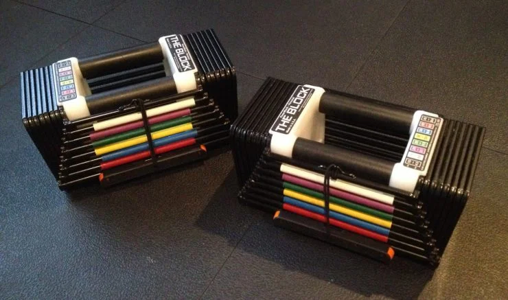 A pair of PowerBlock Elite adjustable dumbbells on a stand.