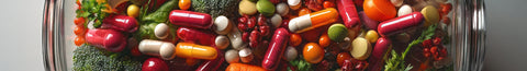 Vitamin pills in a bottle next to fresh green vegetables.