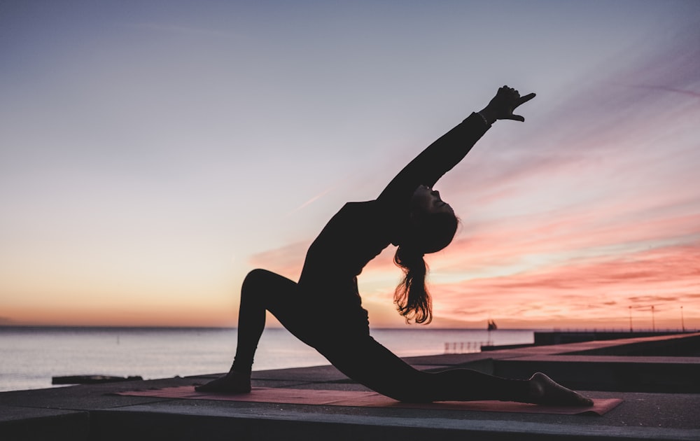 A woman practicing yoga and muscle relaxation techniques on a mat.