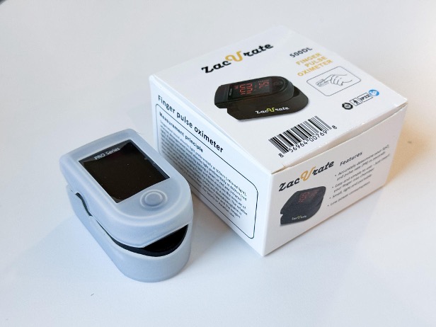 A person's finger inserted into a Zacurate pulse oximeter to measure blood oxygen levels.