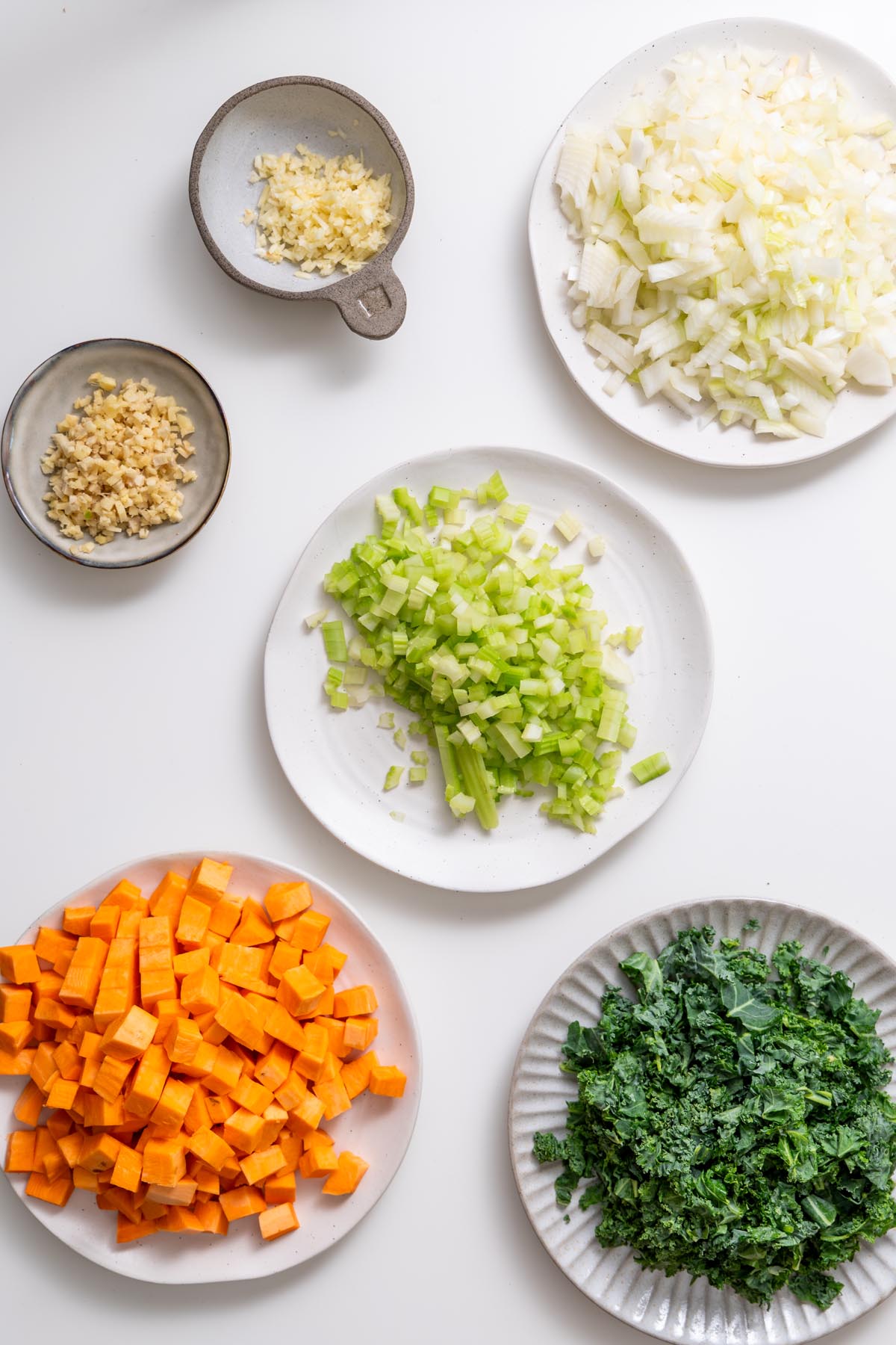 Prepped plates of chopped sweet potatoes, onions, and greens.