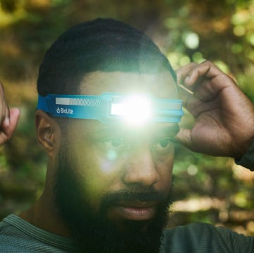 A runner wearing a headlamp on a trail at dusk