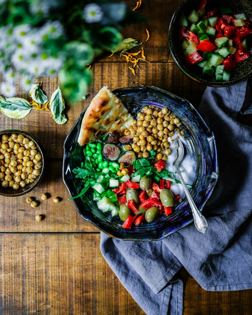 A smiling person enjoying a large, fresh green salad in a bright setting.