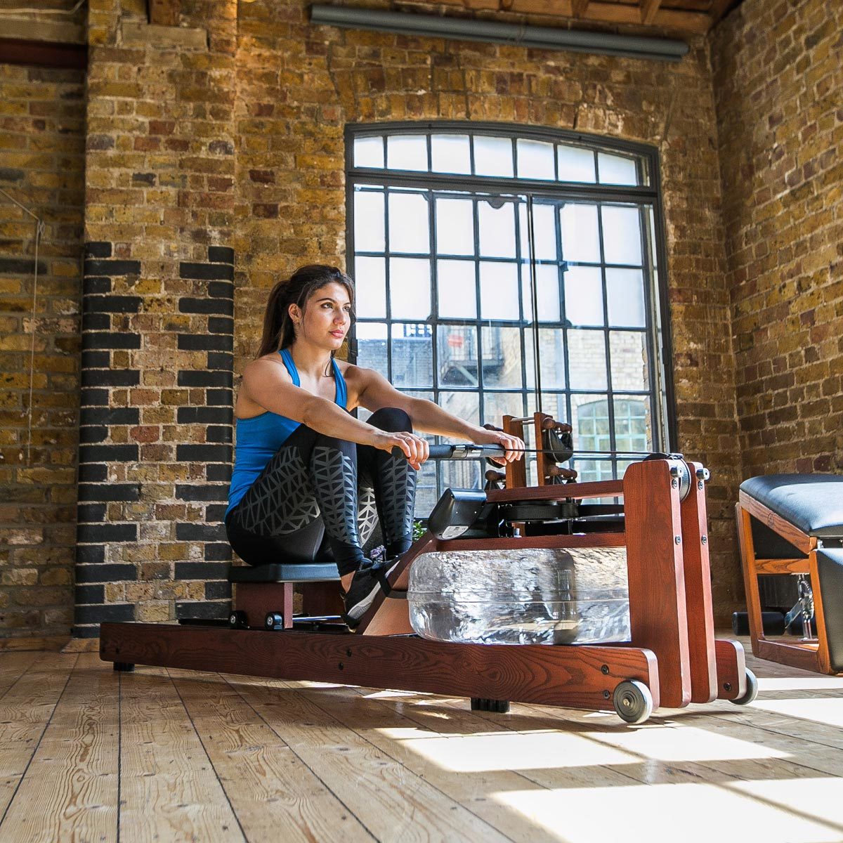 WaterRower Club S4 placed in a modern home gym setting next to a window.