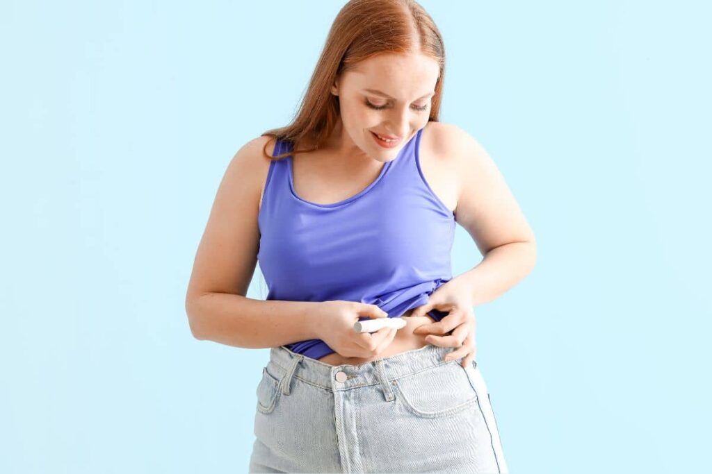 A woman administering a weight loss medication injection in the abdomen area.