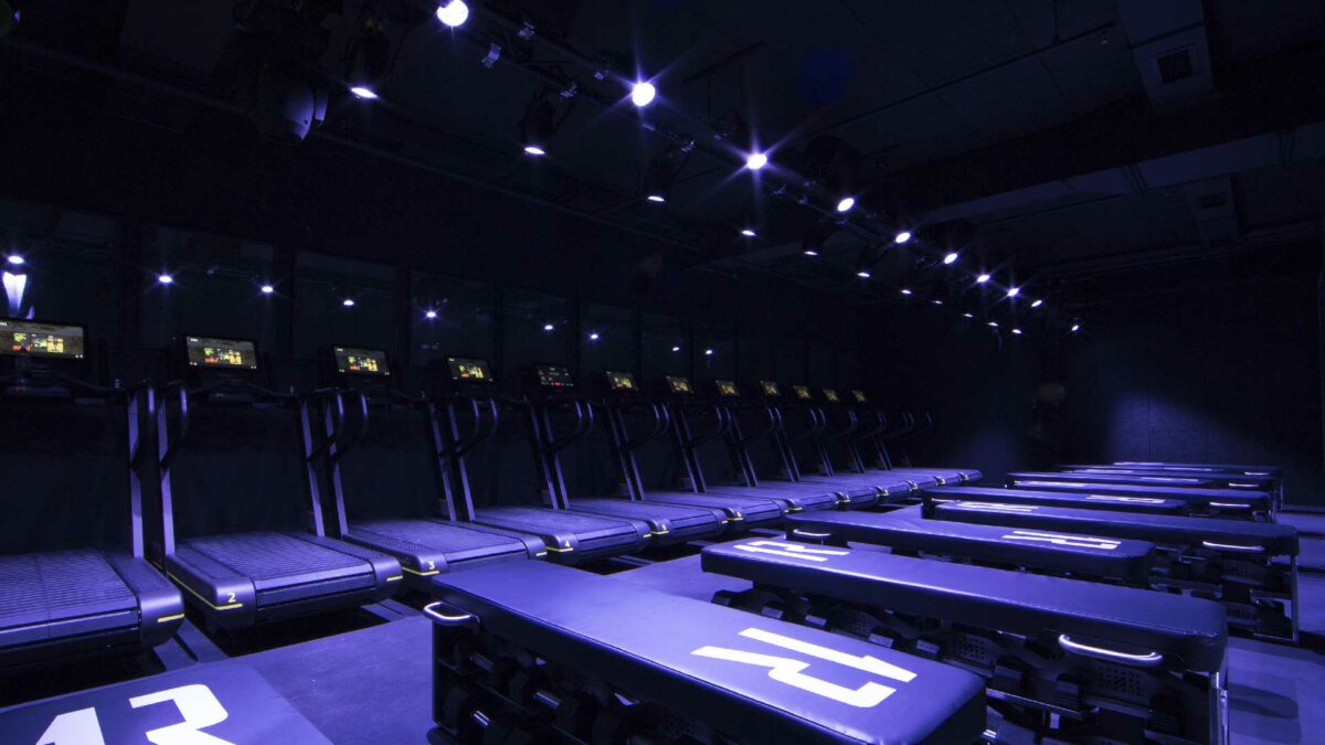 1Rebel Reshape studio with immersive blue and purple lighting and rows of treadmills