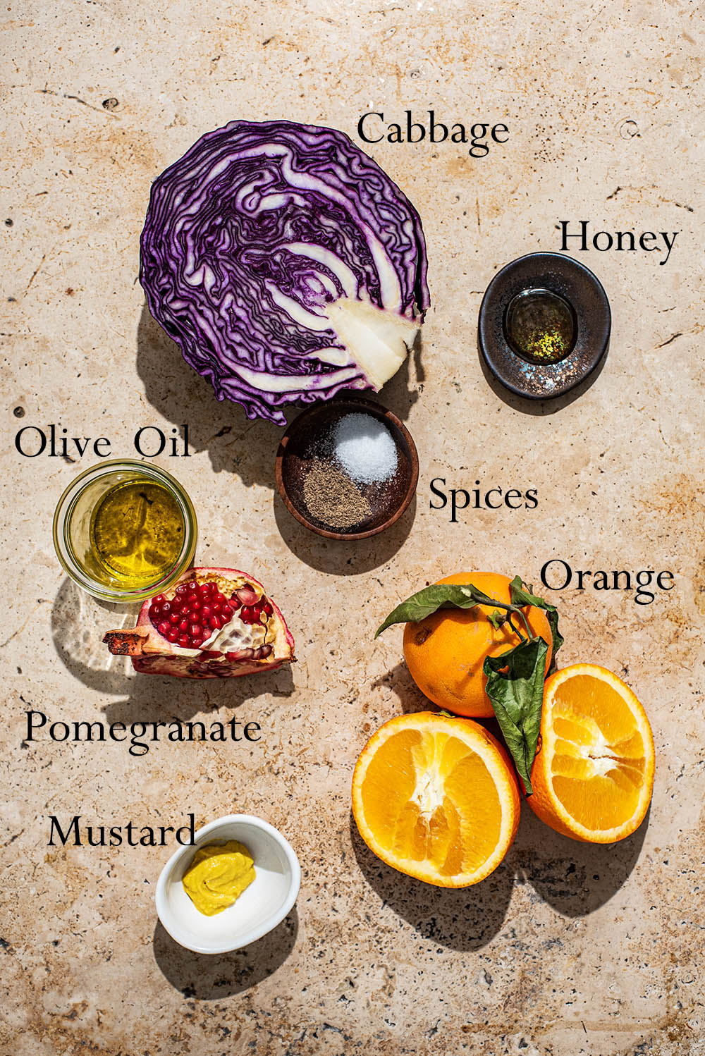 Overhead view of raw ingredients including red cabbage, orange slices, and pomegranate seeds.