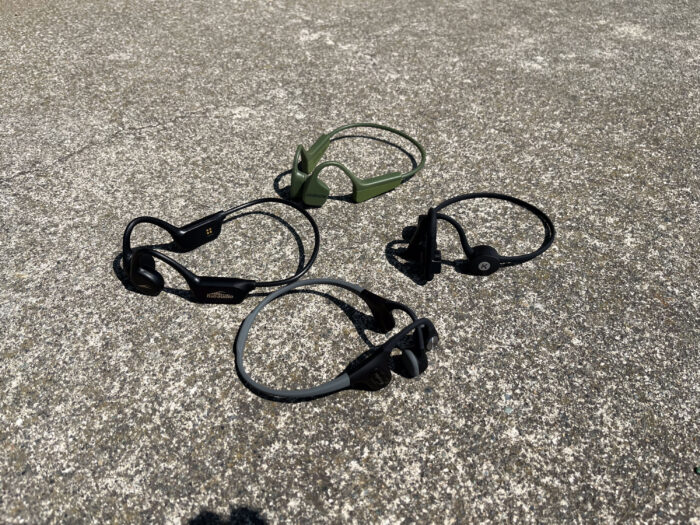 A collection of various bone conduction headphones being prepared for a 2024 comparison guide.