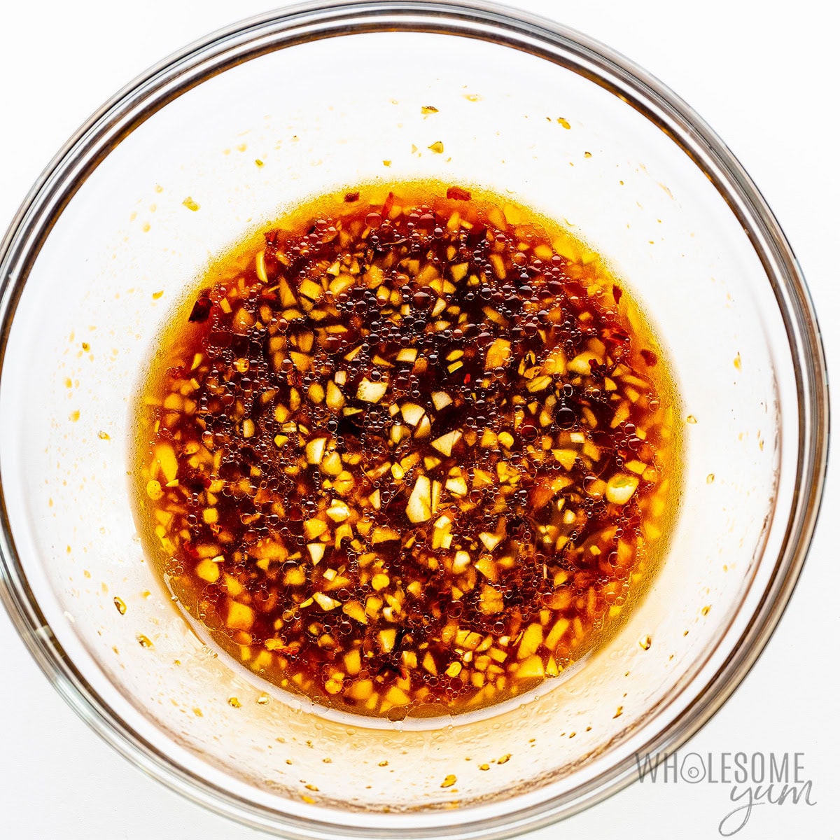 A glass bowl containing a dark whisked marinade for tuna steaks.