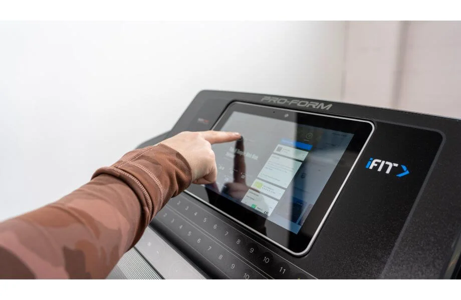 Close-up of a person interacting with the high-definition touchscreen console on a ProForm treadmill.
