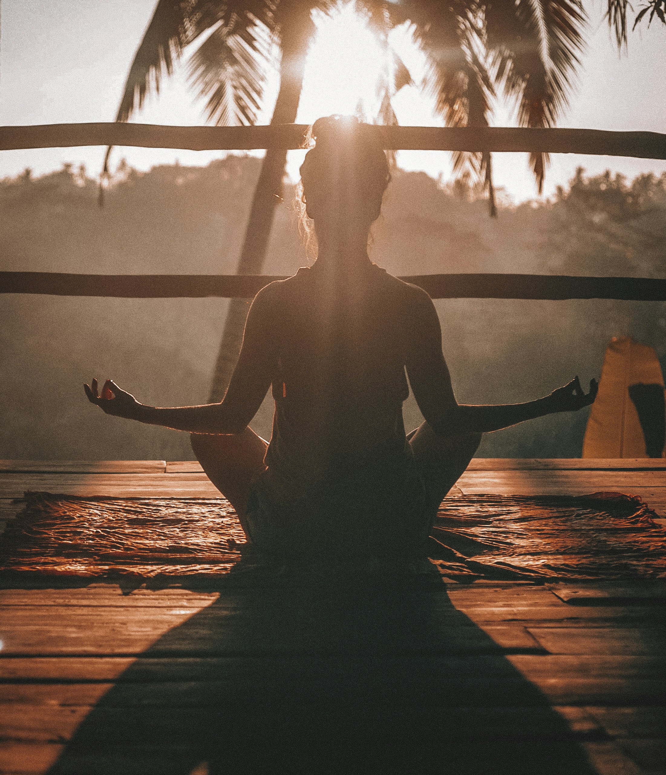 A woman practicing yoga and mindfulness in a quiet, sunlit room.