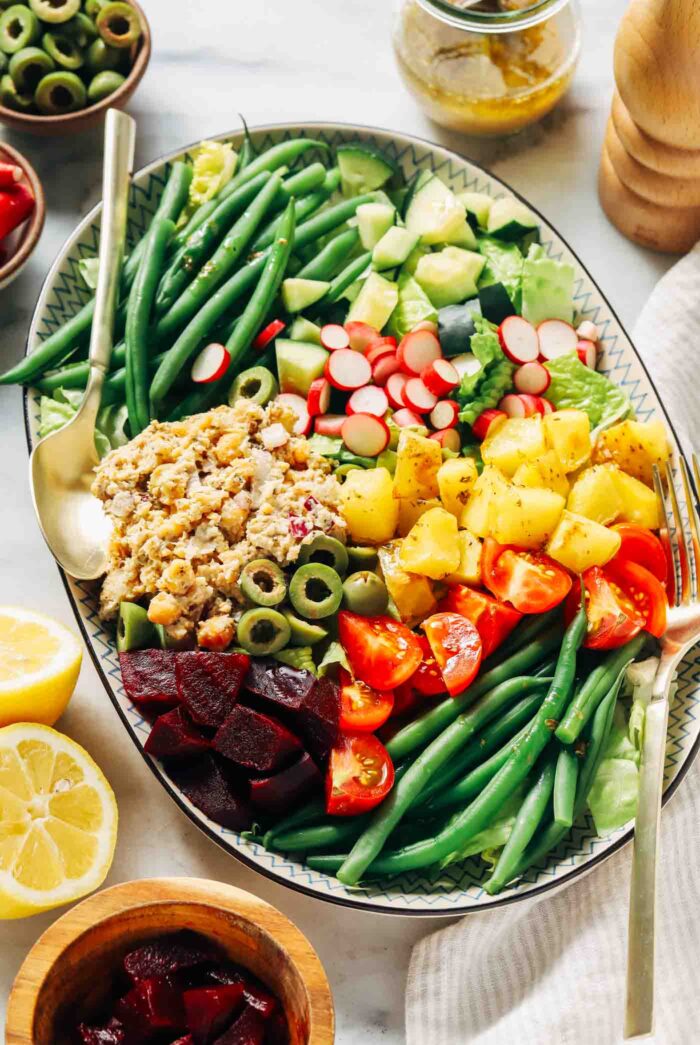 A fully assembled vegetarian Niçoise salad ready to be served on a dining table.